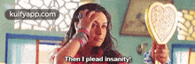a woman is holding a heart shaped mirror and says then i plead insanity .