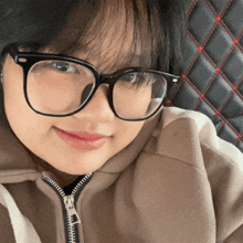 a woman wearing glasses and a brown hoodie