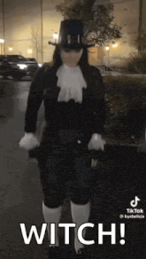 a woman in a witch costume is standing in a parking lot holding an umbrella .