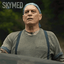 a man wearing suspenders and a bandana with skymed written on the bottom