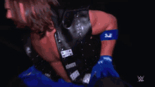 a man wearing a black vest and blue gloves with the letters w on his arm