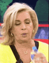 a woman in a yellow shirt is holding a bottle of water