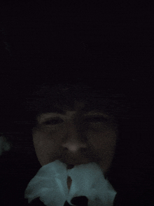 a person covering their mouth with a tissue in a dark room