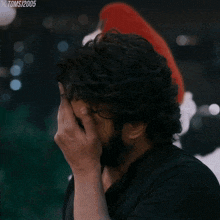 a man with a beard covering his face with his hand