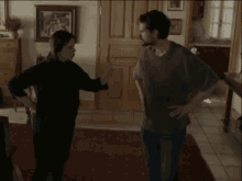 a woman is standing in a living room with a rug and a painting on the wall