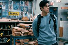 a man with a backpack is standing in front of a warning construction area sign