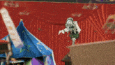 a clown is standing in front of a red curtain with chinese writing