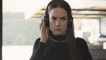a woman wearing headphones looks at the camera with an angry look on her face