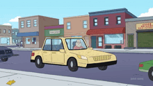 a yellow car is driving down a street in front of a store that says toms holes