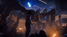 a man is standing in front of a giant monster in a dark room .