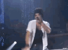 a man in a white jacket is dancing on a stage in front of a microphone .