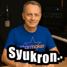 a man wearing a blue starmaker shirt sits at a desk
