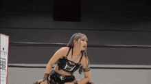 a woman in a black crop top is standing next to another woman in a wrestling ring .