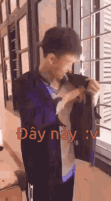 a man is taking off his jacket in front of a window with the words day nay : v written in red .