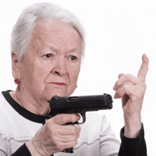an elderly woman is holding a gun and pointing