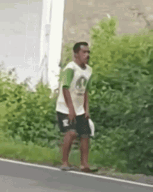 a man in a white shirt and green shorts is walking down a road