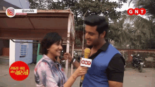 a man is being interviewed by a woman who is wearing a gnt microphone
