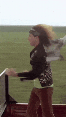 a woman in a black jacket and headband is standing in front of a field