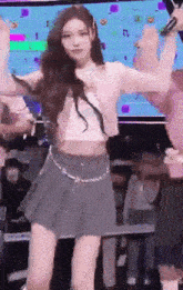 a woman in a crop top and a pleated skirt is dancing