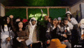 a group of people are standing next to each other in a room with a green wall .