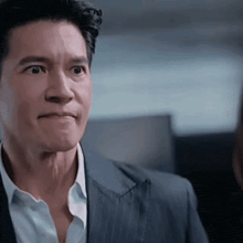 a man in a suit and white shirt is looking at the camera