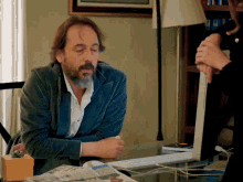a man with a beard sits at a desk with a newspaper on it