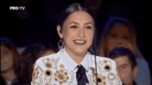 a woman is smiling in front of a microphone with pro tv written on the bottom