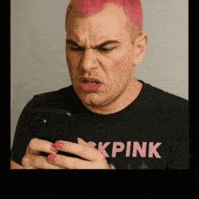 a man with pink hair wearing a black shirt that says kpink