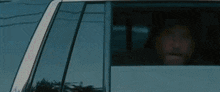 a man is sitting in a car looking out the window .