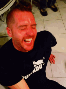 a man wearing a black shirt with a cat on it laughs