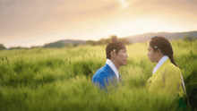 a man and a woman are standing in a field of tall grass