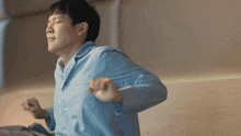a man in a blue shirt is stretching his arms out