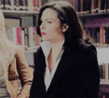 a woman in a black jacket and white shirt stands next to another woman