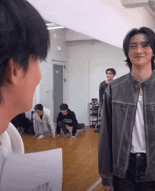 a man in a leather jacket is looking at another man