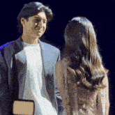 a man in a suit and a woman in a pink dress are looking into each other 's eyes