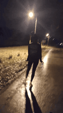 a person walking down a road at night with a bottle of water in their hand