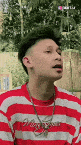 a young man wearing a red and white striped shirt and a chain around his neck