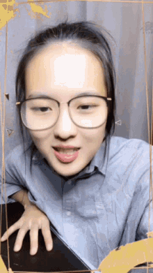 a young woman wearing glasses and a blue shirt is making a funny face