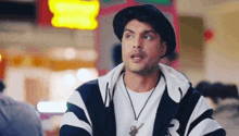 a man wearing a hat and a striped jacket is looking at the camera .