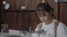 a woman in an apron sits in front of a sink with a toi logo in the corner