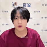 a young man wearing a maroon t-shirt with jendongists written on the bottom