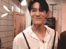 a man wearing a white shirt and suspenders is smiling in a room .