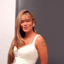 a woman in a white dress with a heart tattoo on her arm