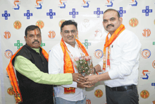 three men are posing for a photo in front of a wall that says one