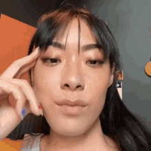 a woman is making a funny face with her hand on her forehead .