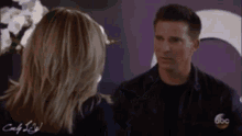 a man and a woman are standing next to each other and talking to each other .
