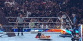 a wrestler is laying on the ground in a wrestling ring while a referee stands behind him .