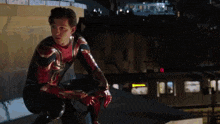 a man in a spiderman suit is sitting on a ledge