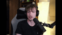 a man wearing headphones and a black shirt is sitting in front of a microphone