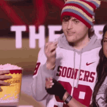 a man in a sooners jersey eating popcorn